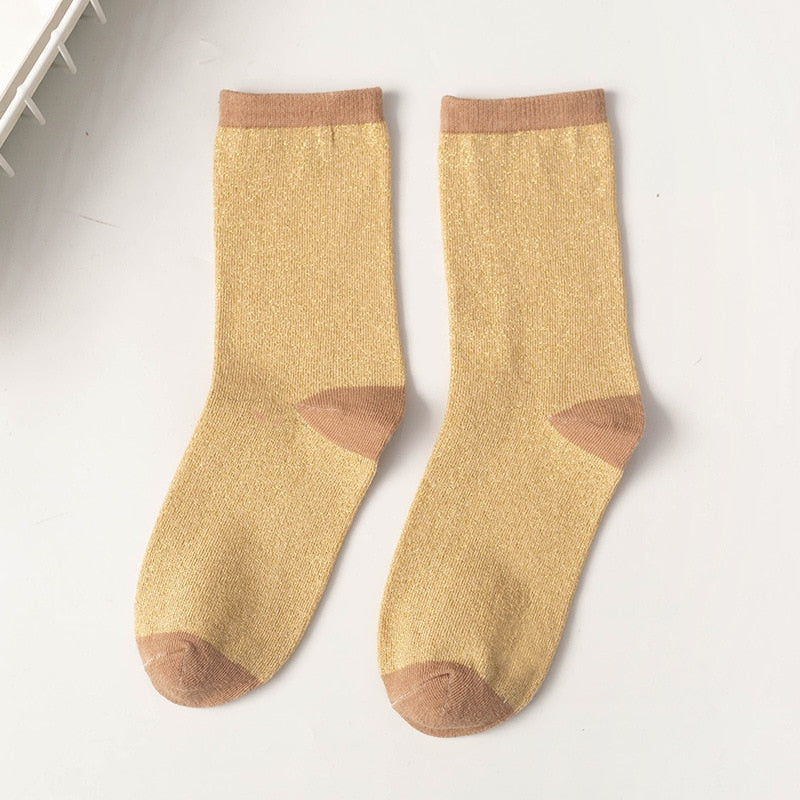 Nærbilde av to forskjellige fargerike unisex glittersokker, viser myk tekstur.