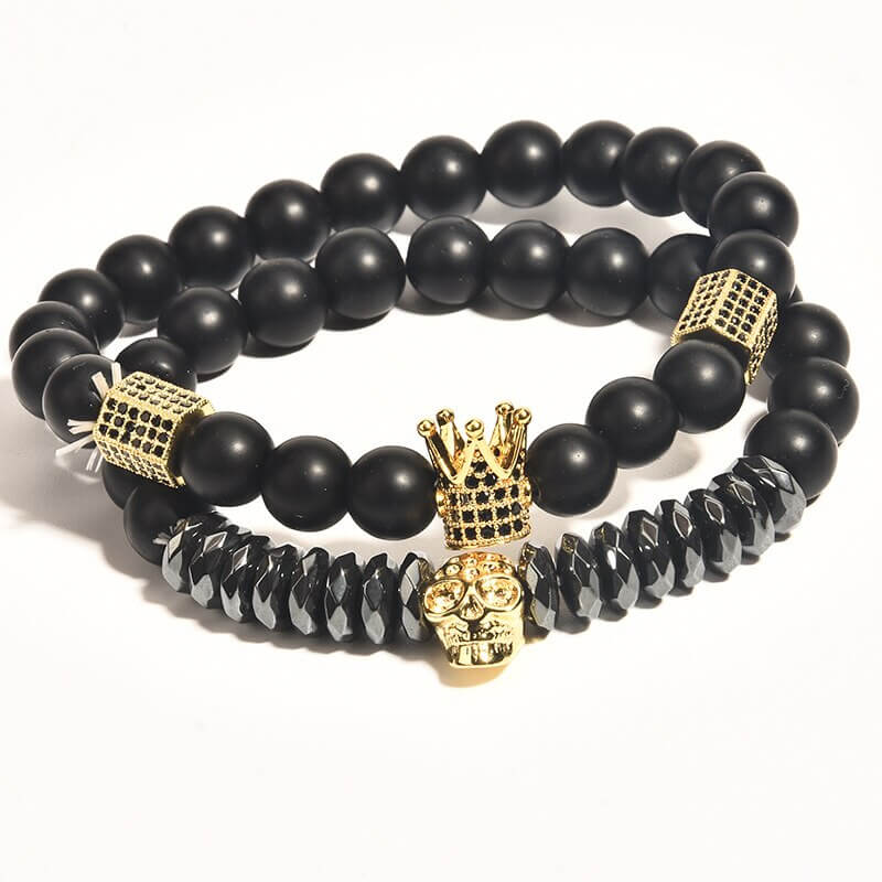 Unisex onyx steinarmbånd med sorte perler, krone og hodeskalle sjarmer. Elegant og beskyttende smykke.