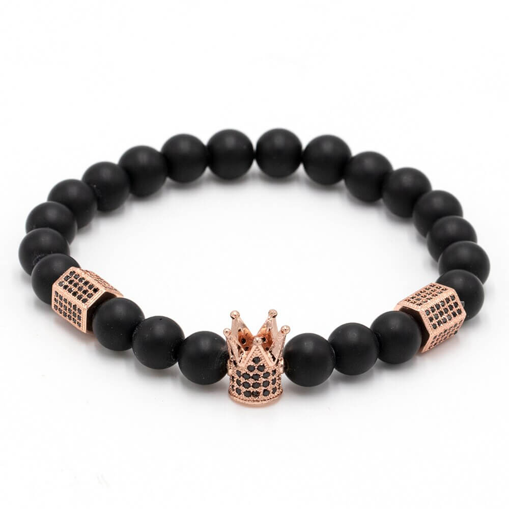 Kraftfullt unisex armbånd i onyx stein for energi og beskyttelse, med unike krone og hodeskalle detaljer.